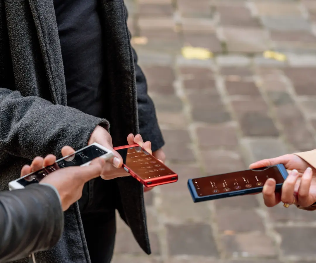 Traja priatelia šťastne držia v rukách svoje prekladače, zapájajú sa do rozhovoru a zdieľajú spoločné chvíle. 