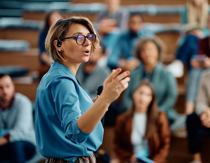 Žena, ktorá prednáša na univerzite a má v uchu slúchadlo Vasco Translator E1.